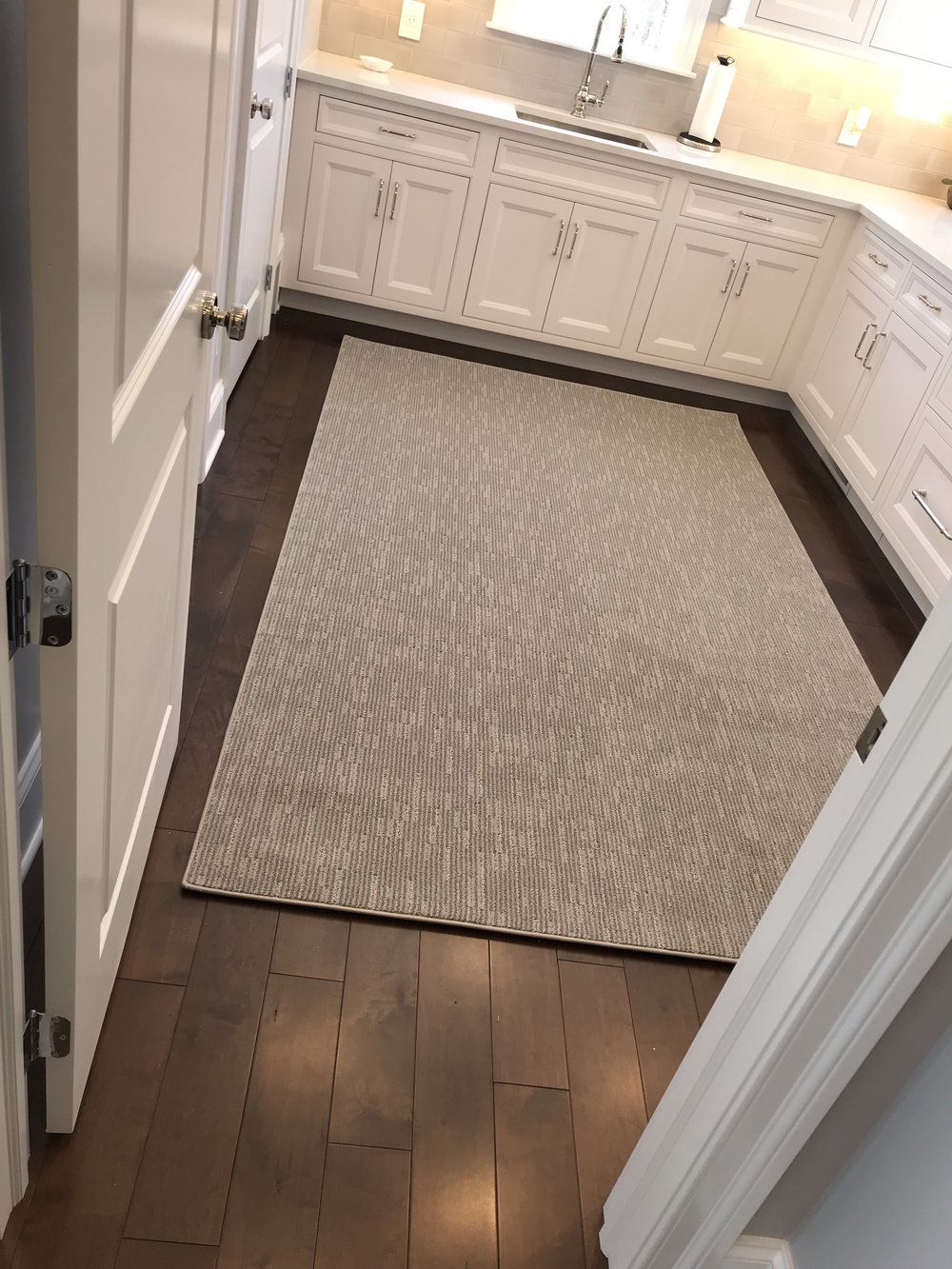 A kitchen with white cabinets and a rug on the floor