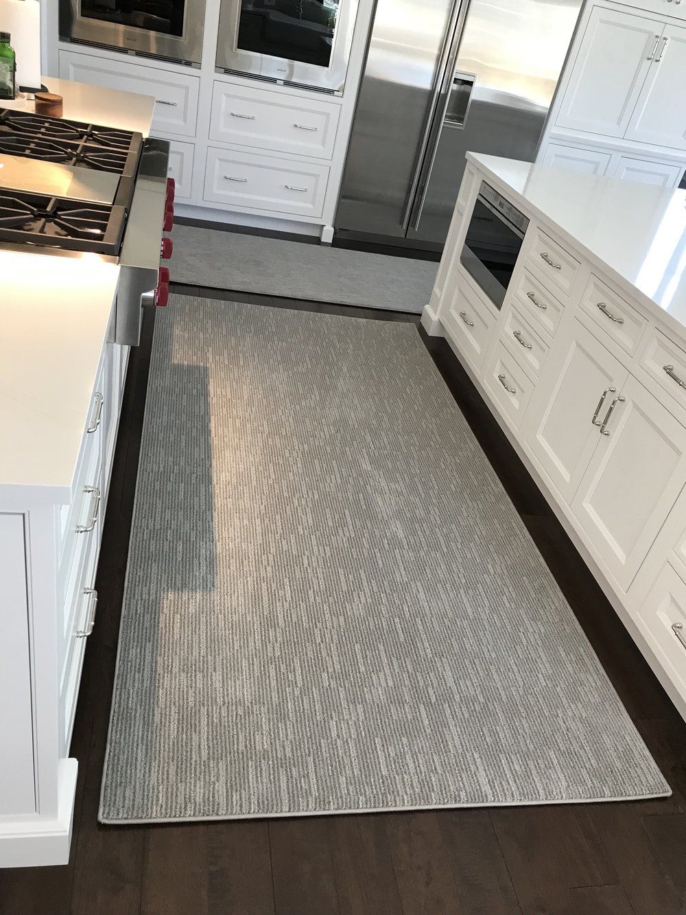 A kitchen with white cabinets and a rug on the floor