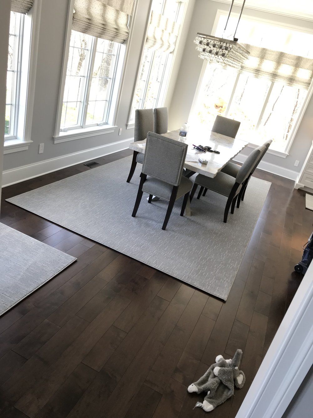 A dining room with a table and chairs and a rug on the floor