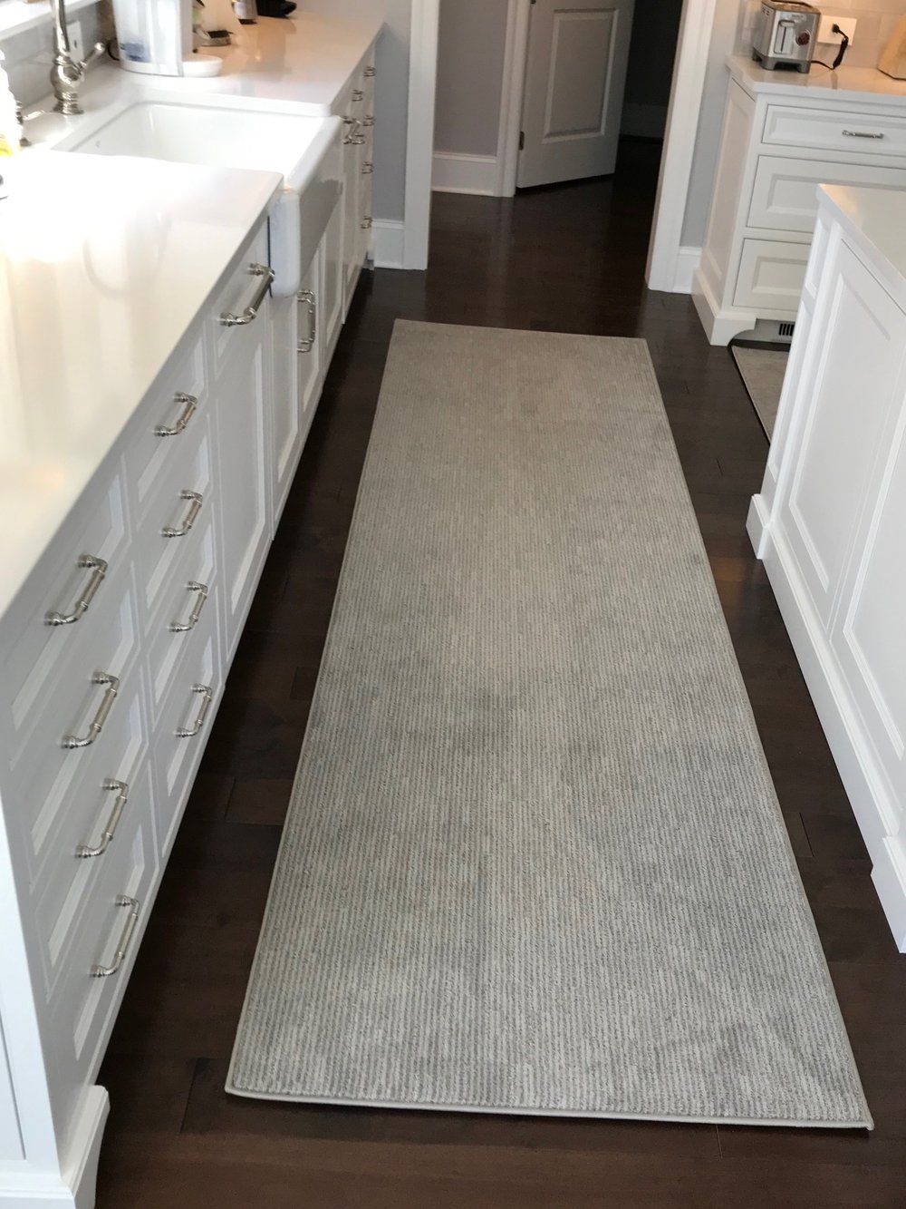 A kitchen with white cabinets and a rug on the floor