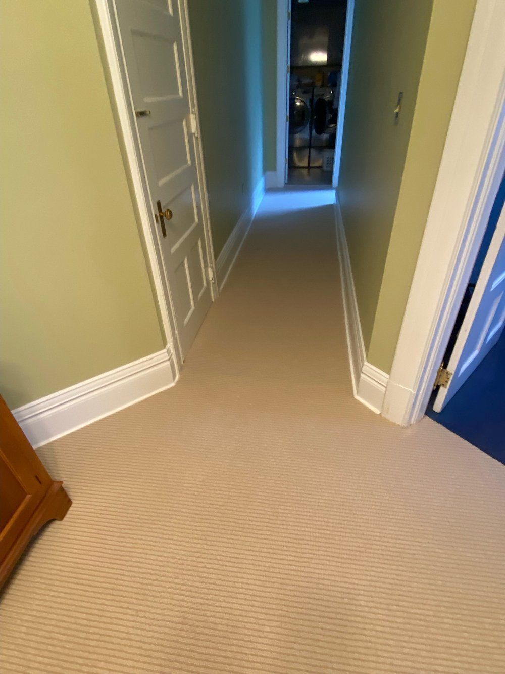 A hallway with a carpeted floor and green walls