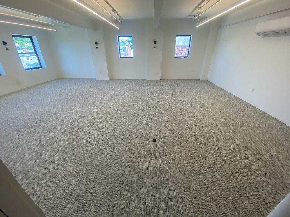 An empty room with a carpeted floor and white walls