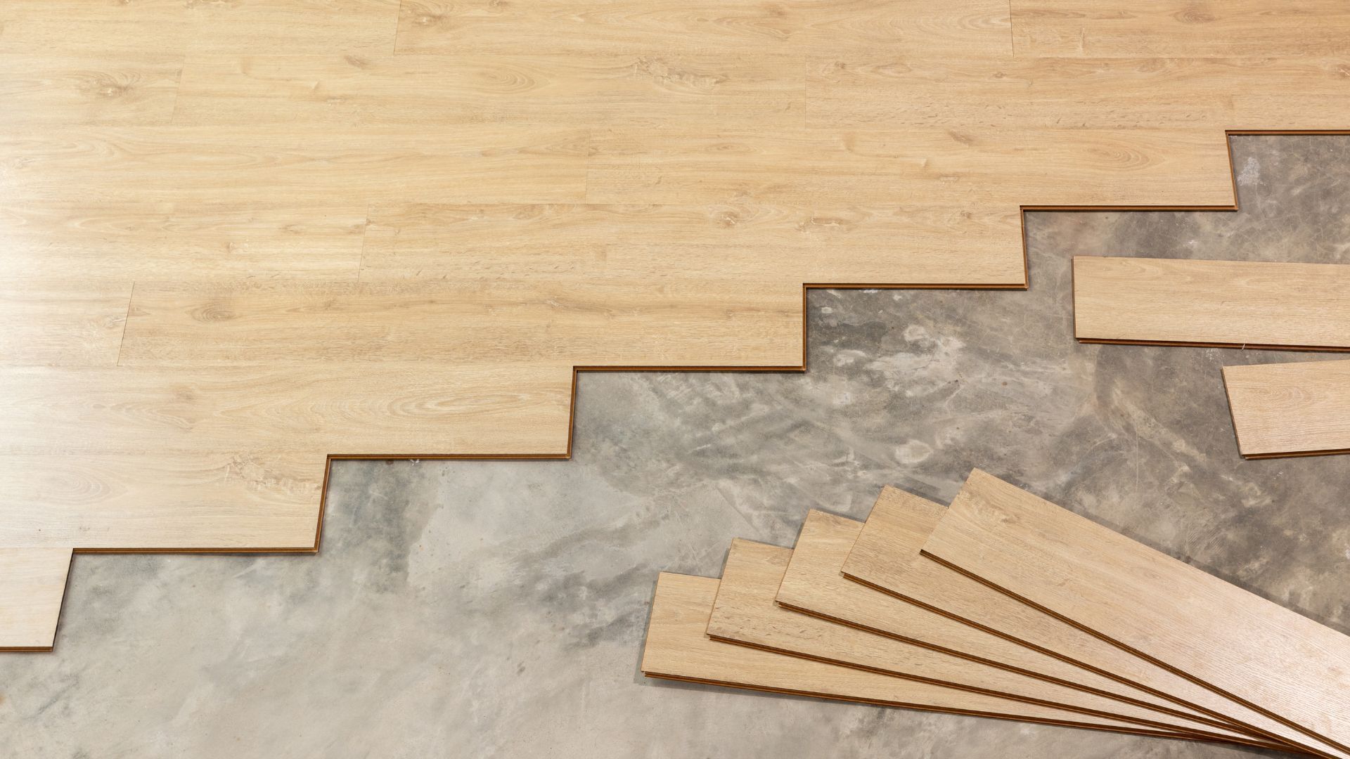 A wooden floor is being installed on a concrete floor.