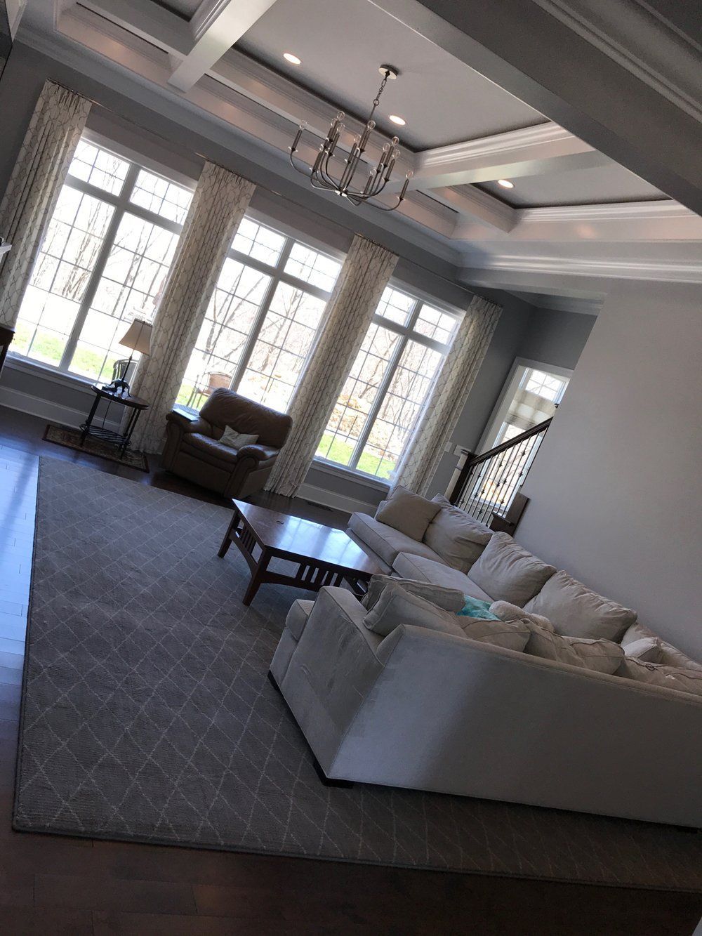 A living room with a couch , chairs , coffee table and windows