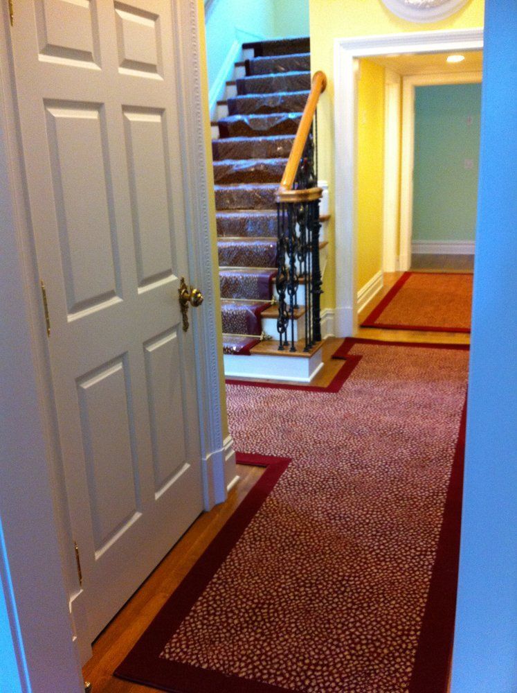A hallway with stairs and a red carpet