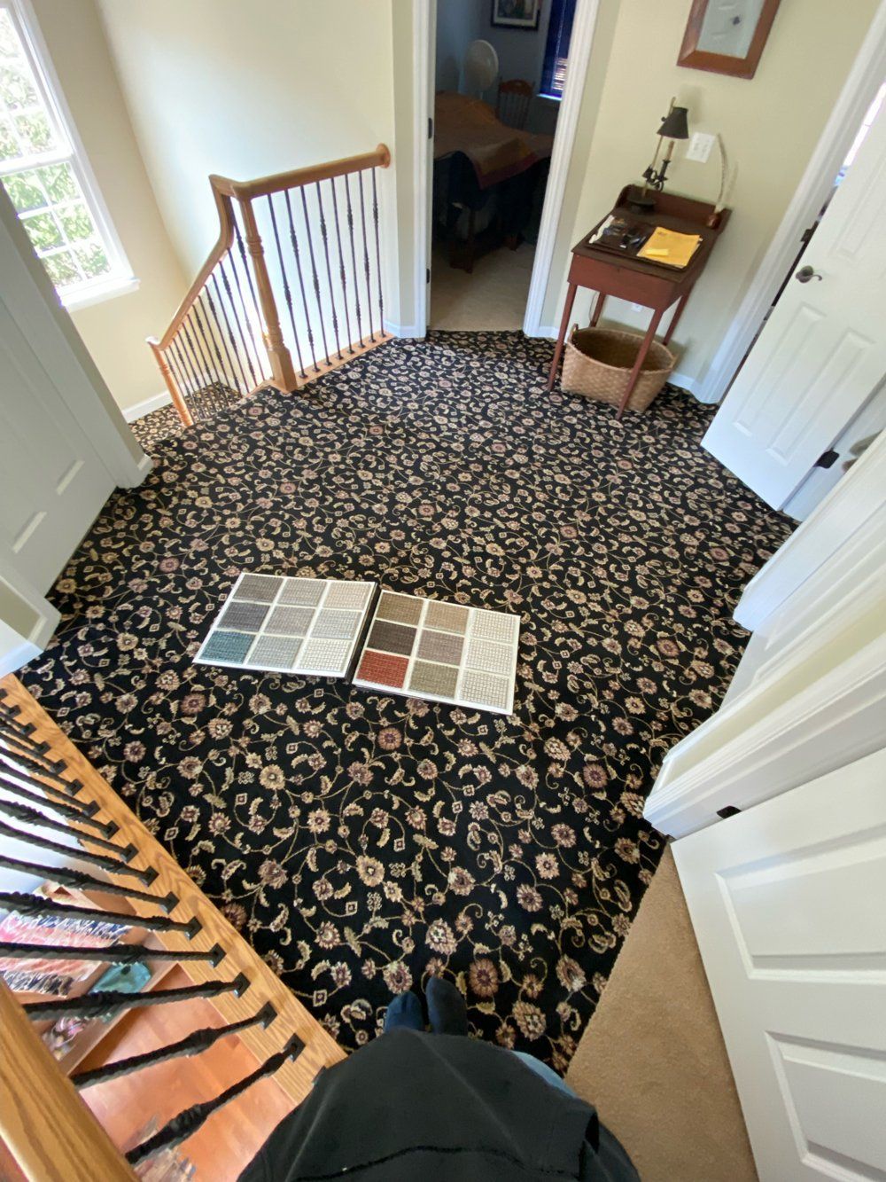A person is standing in a hallway with a carpet and a book on the floor.