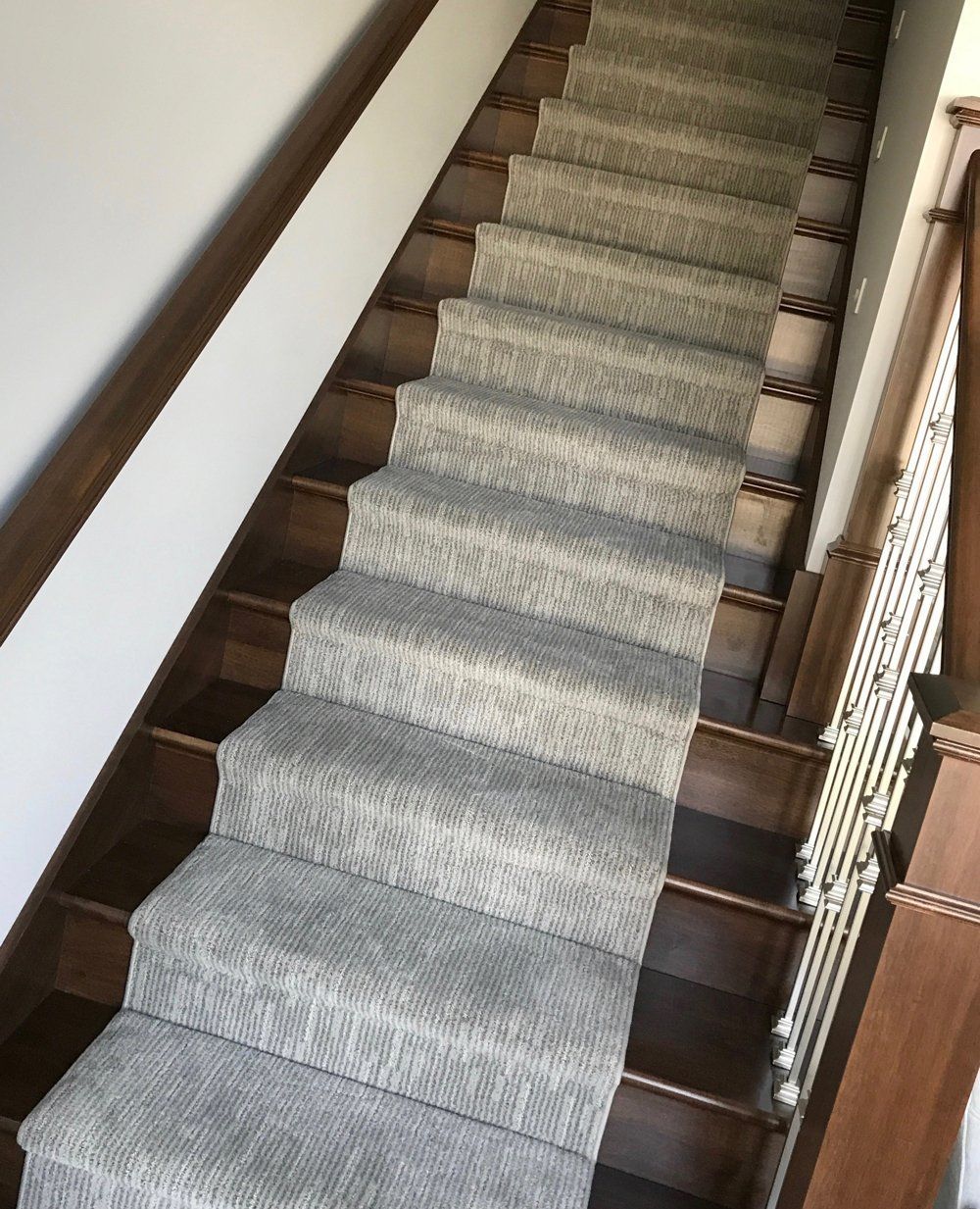 A staircase with a carpet on the steps and a wooden railing