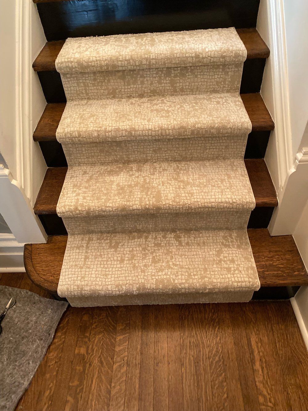 A staircase with a carpet on the steps and a rug on the floor.