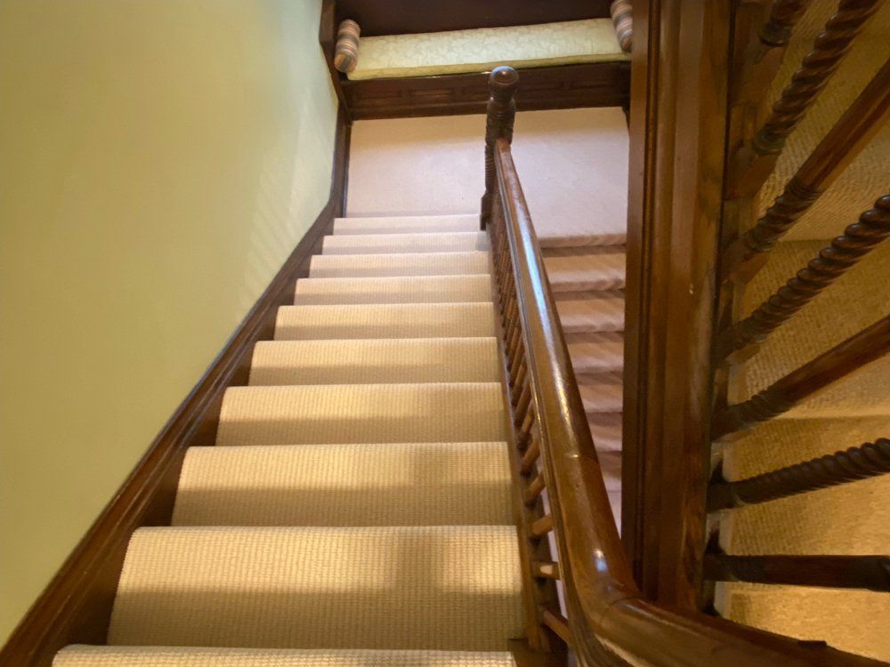 A staircase with a wooden railing and carpeted steps
