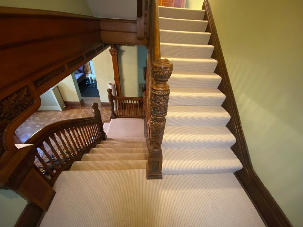 A staircase with a wooden railing and white carpet