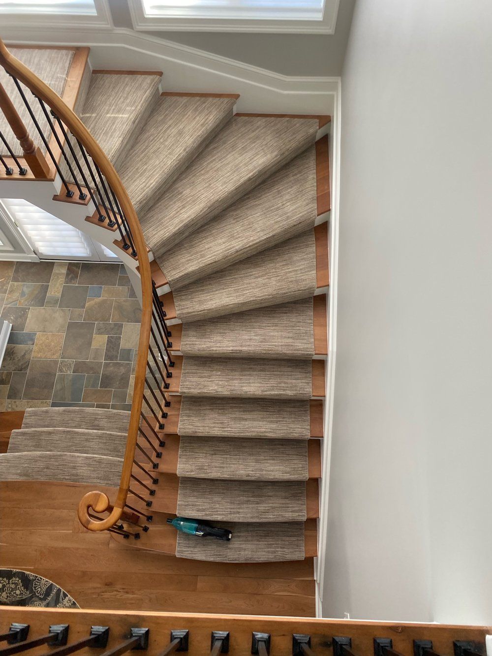 A spiral staircase with a wooden railing and a carpeted staircase