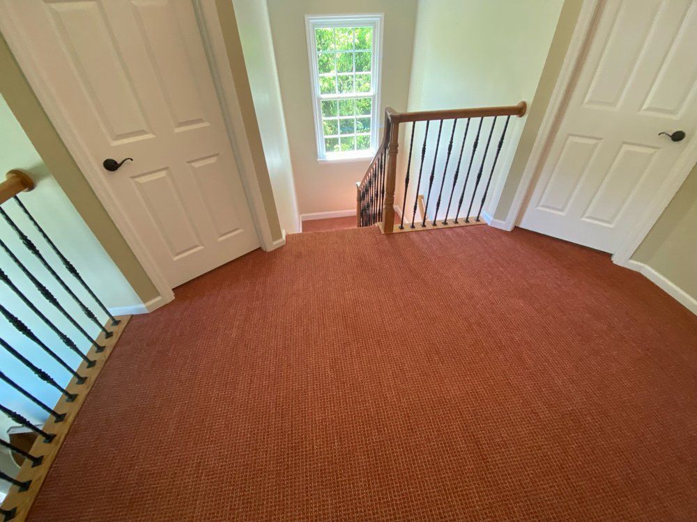 A staircase with a red carpet and a window.