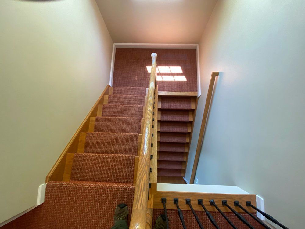A staircase with a red carpet and a wooden railing