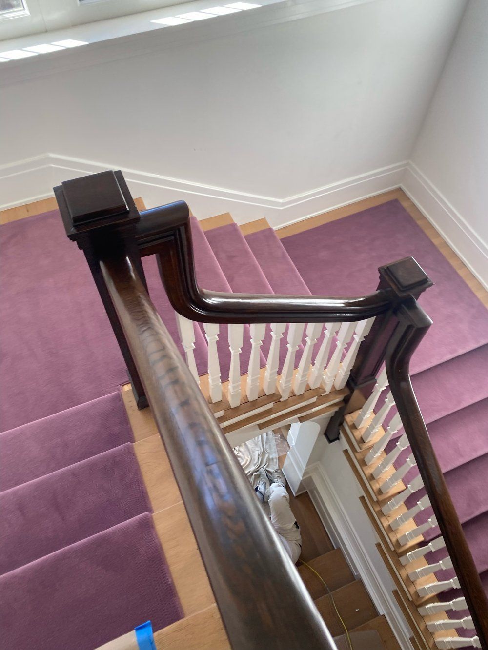 A staircase with purple carpet and a wooden railing