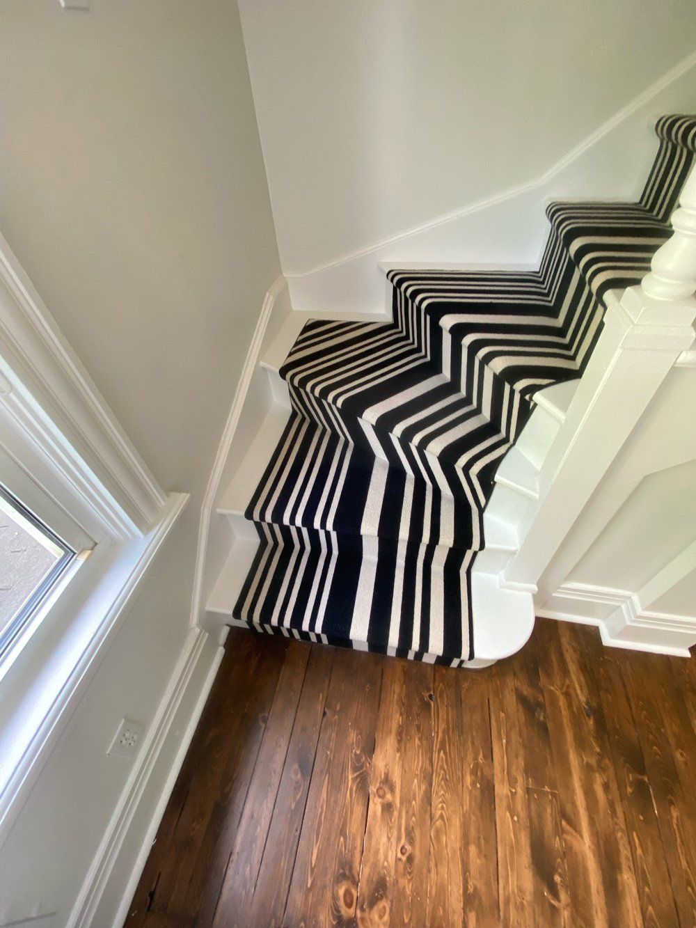 A staircase with a black and white striped carpet