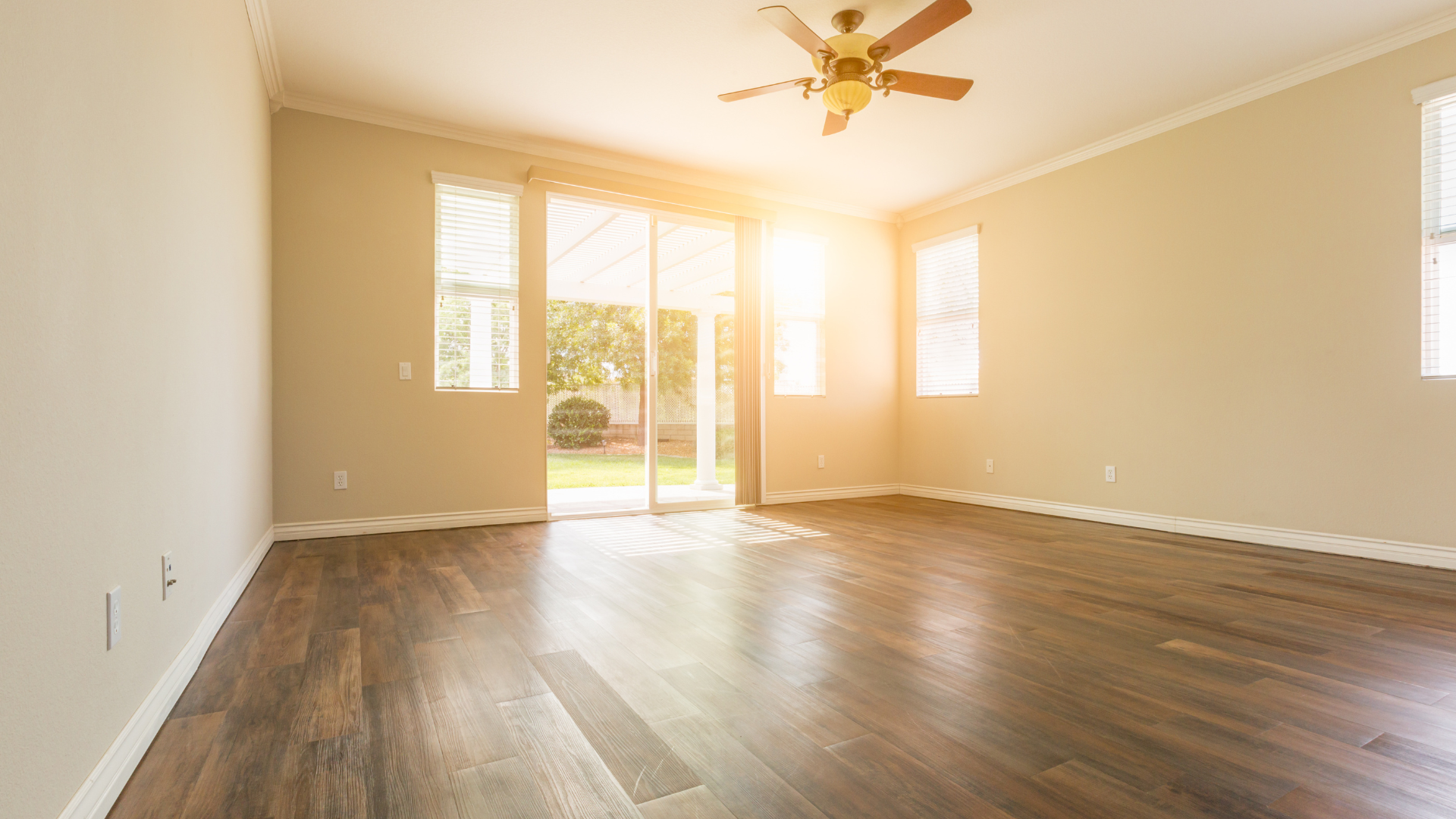An empty living room with hardwood floors and a ceiling fan.