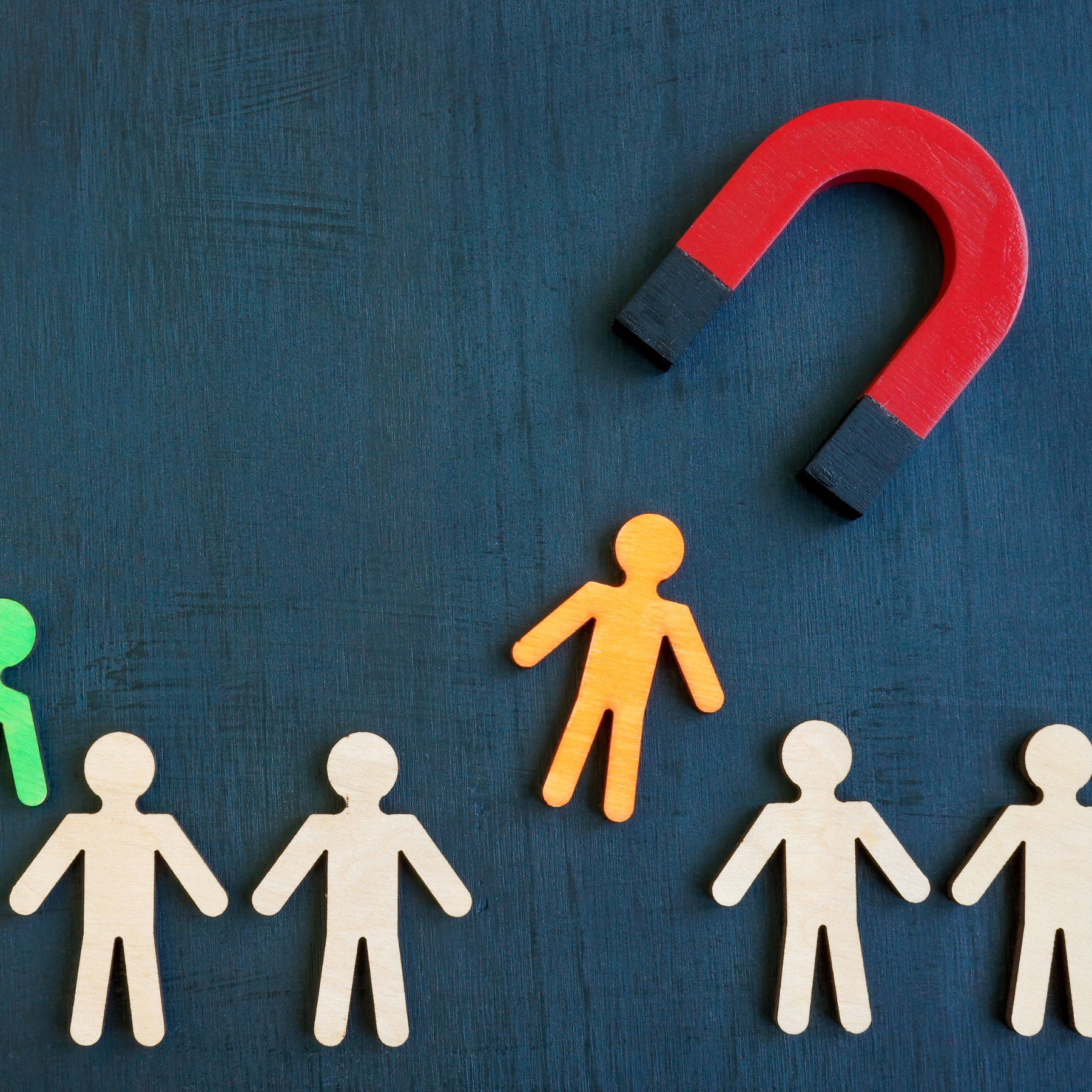 A group of paper people standing next to a red magnet