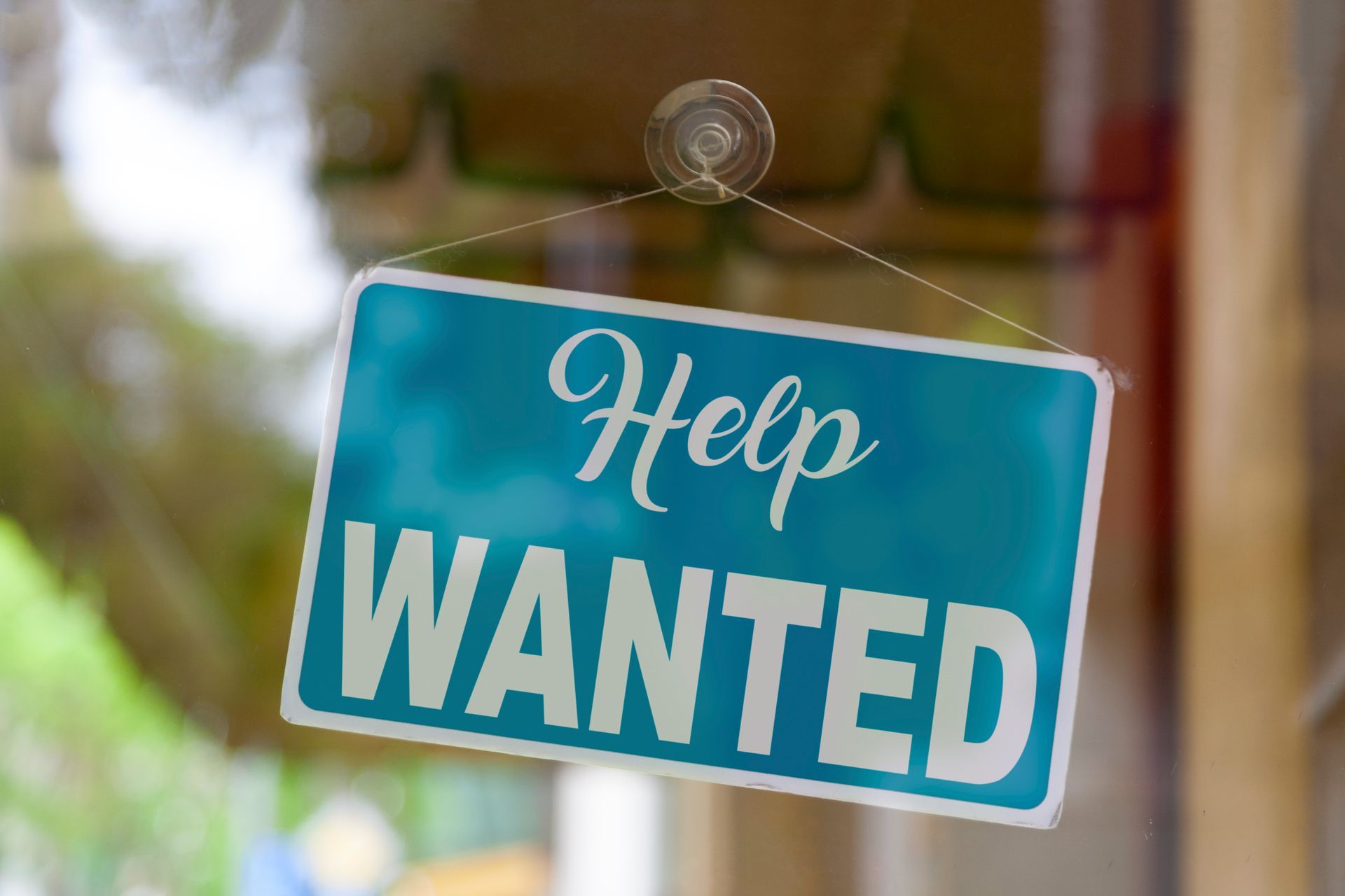 A help wanted sign is hanging on a window.