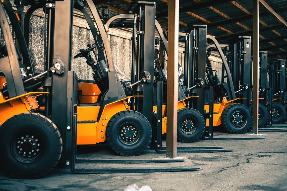 Row of Orange Forklifts Parked Inside a Warehouse Near Stacked Pallets — Lifters Hire in Cambridge, TAS