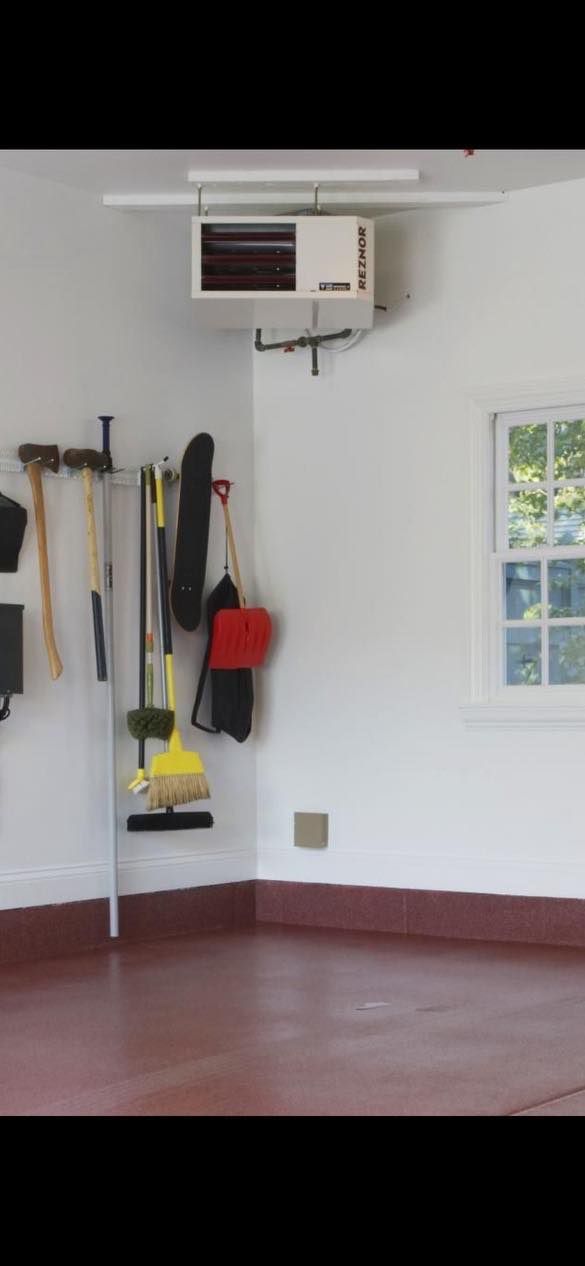 A garage with a lot of tools hanging on the wall and a window.