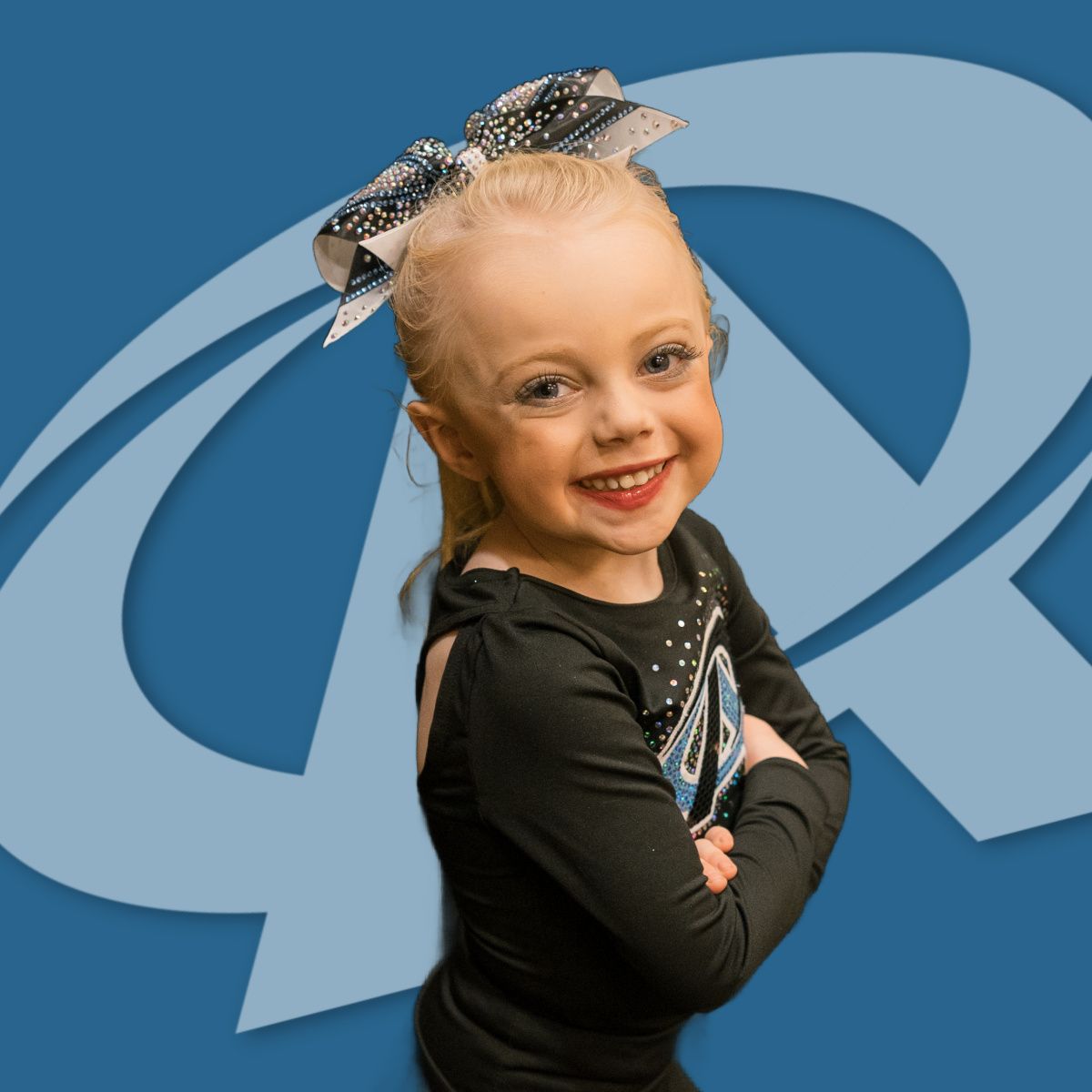 A little girl with a bow in her hair is smiling in front of a blue letter r