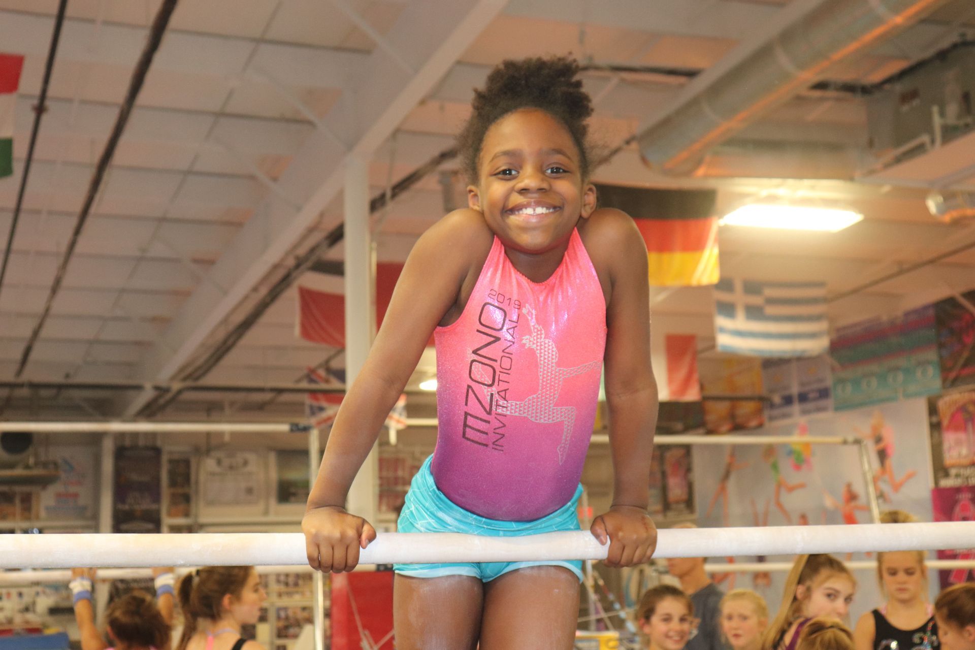 A young girl is standing on a balance beam in a gym.