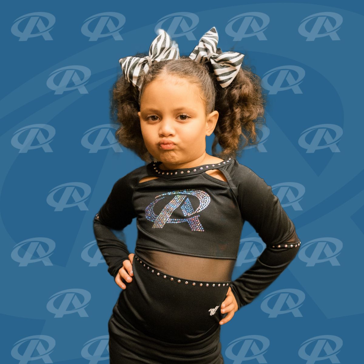 A little girl wearing a black top with the letter r on it
