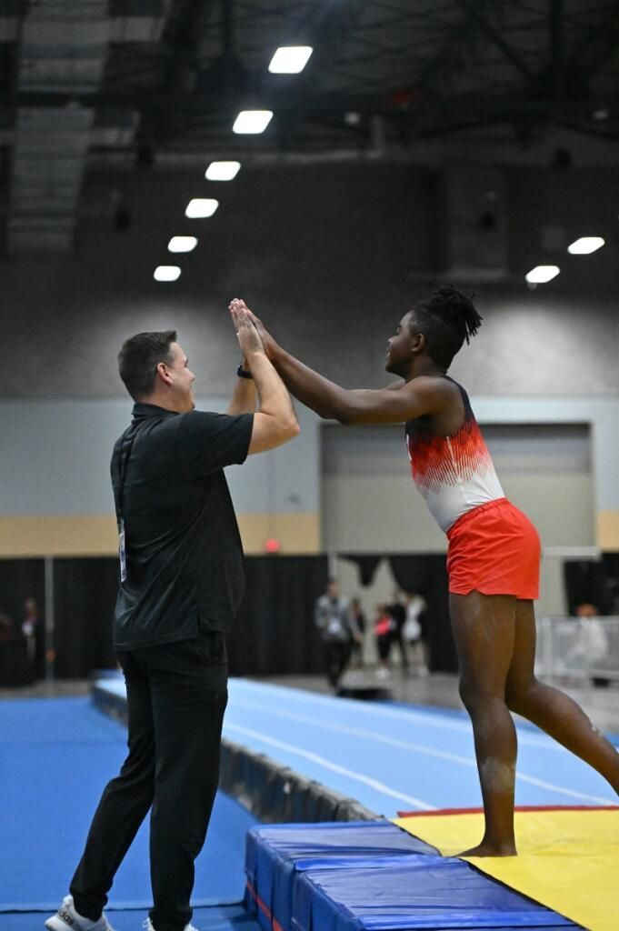 A man and a woman are giving each other a high five in a gym.