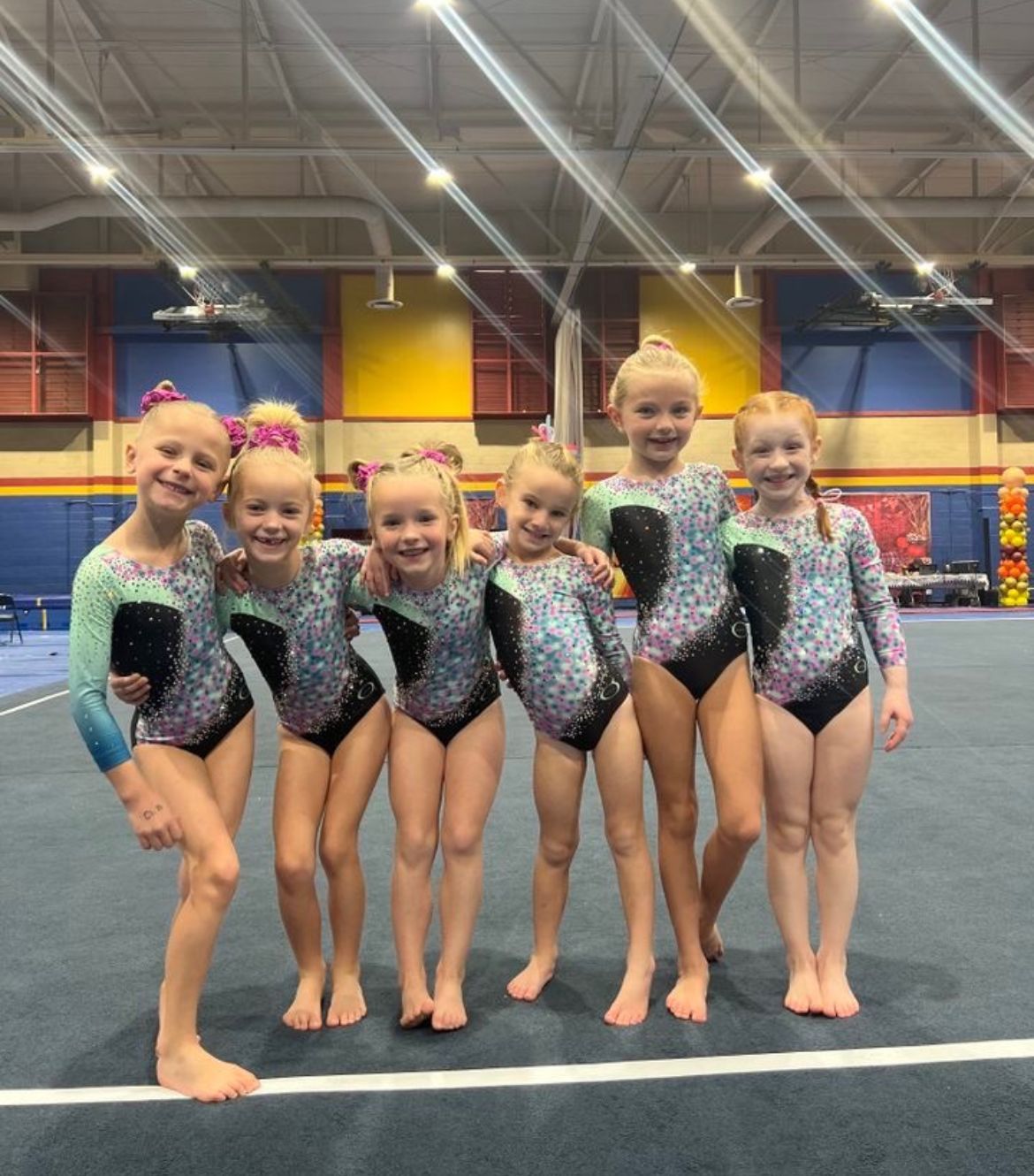 A group of young girls are posing for a picture in a gym