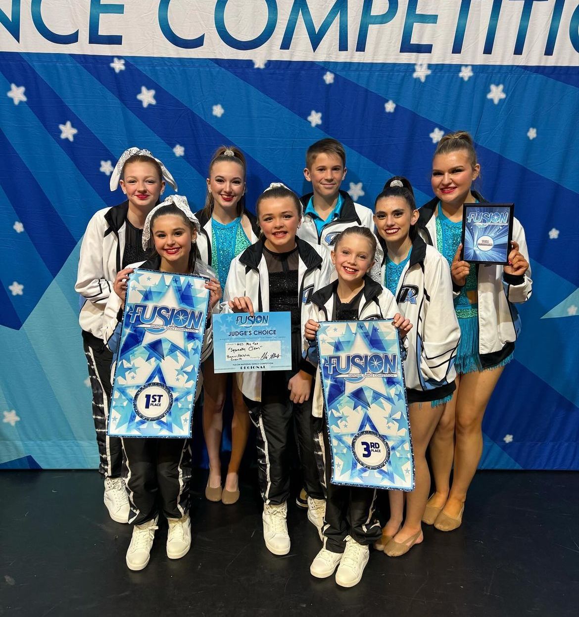 A group of young people are posing for a picture in front of a competition banner