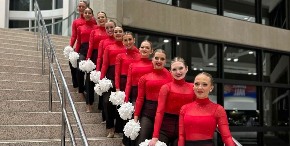 A group of cheerleaders are standing on a set of stairs holding pom poms.