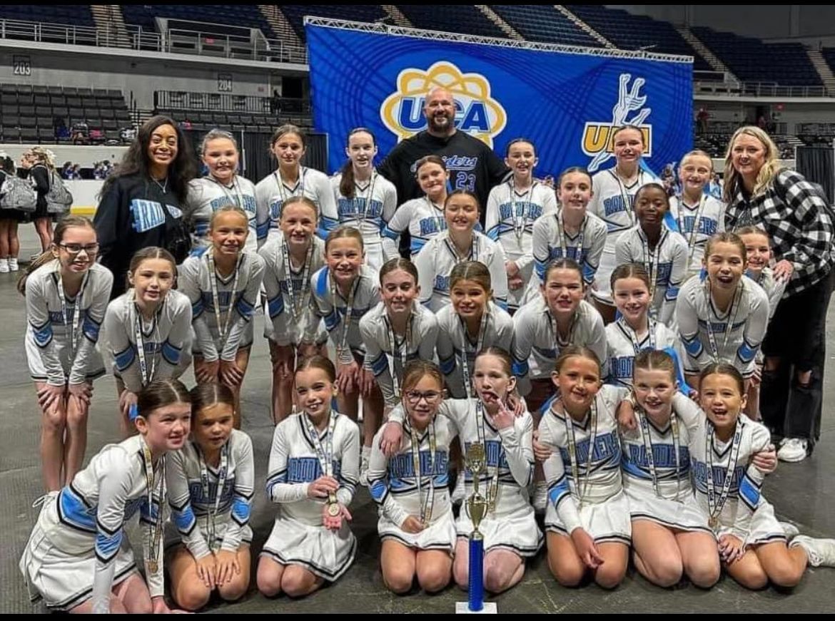 A group of cheerleaders are posing for a picture in a stadium.