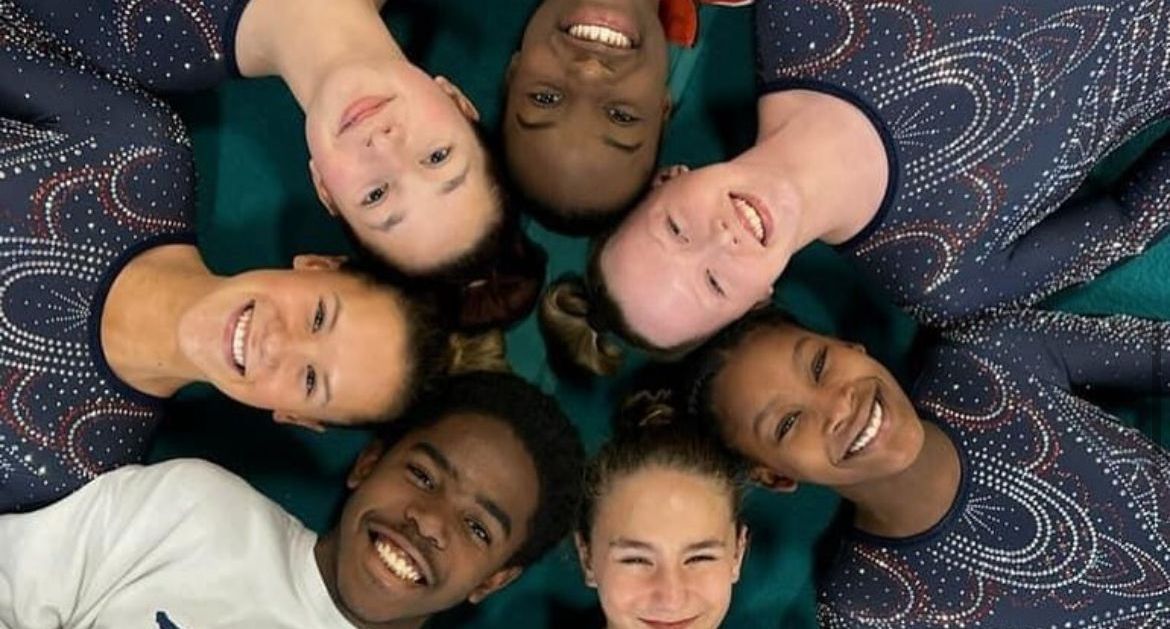 A group of people are laying in a circle and smiling.