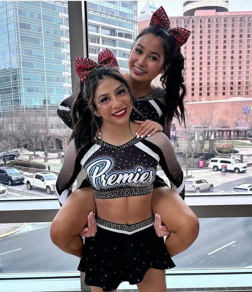 Two cheerleaders wearing premier uniforms are posing for a picture