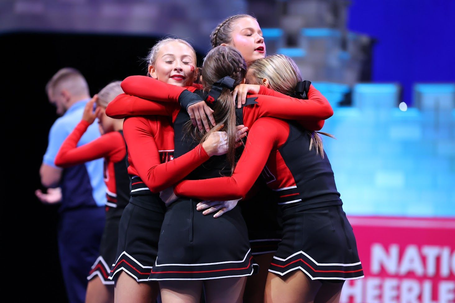 A group of cheerleaders are hugging each other in a huddle