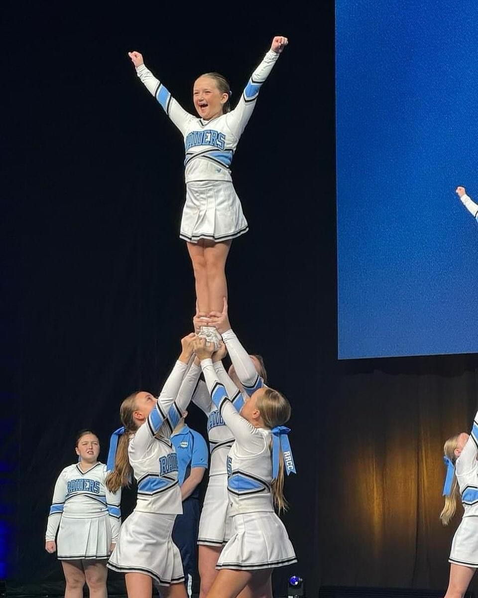 A group of cheerleaders are performing a stunt on a stage.