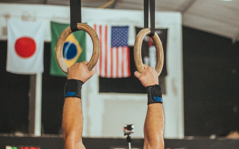 A man is hanging from gymnastic rings in a gym.