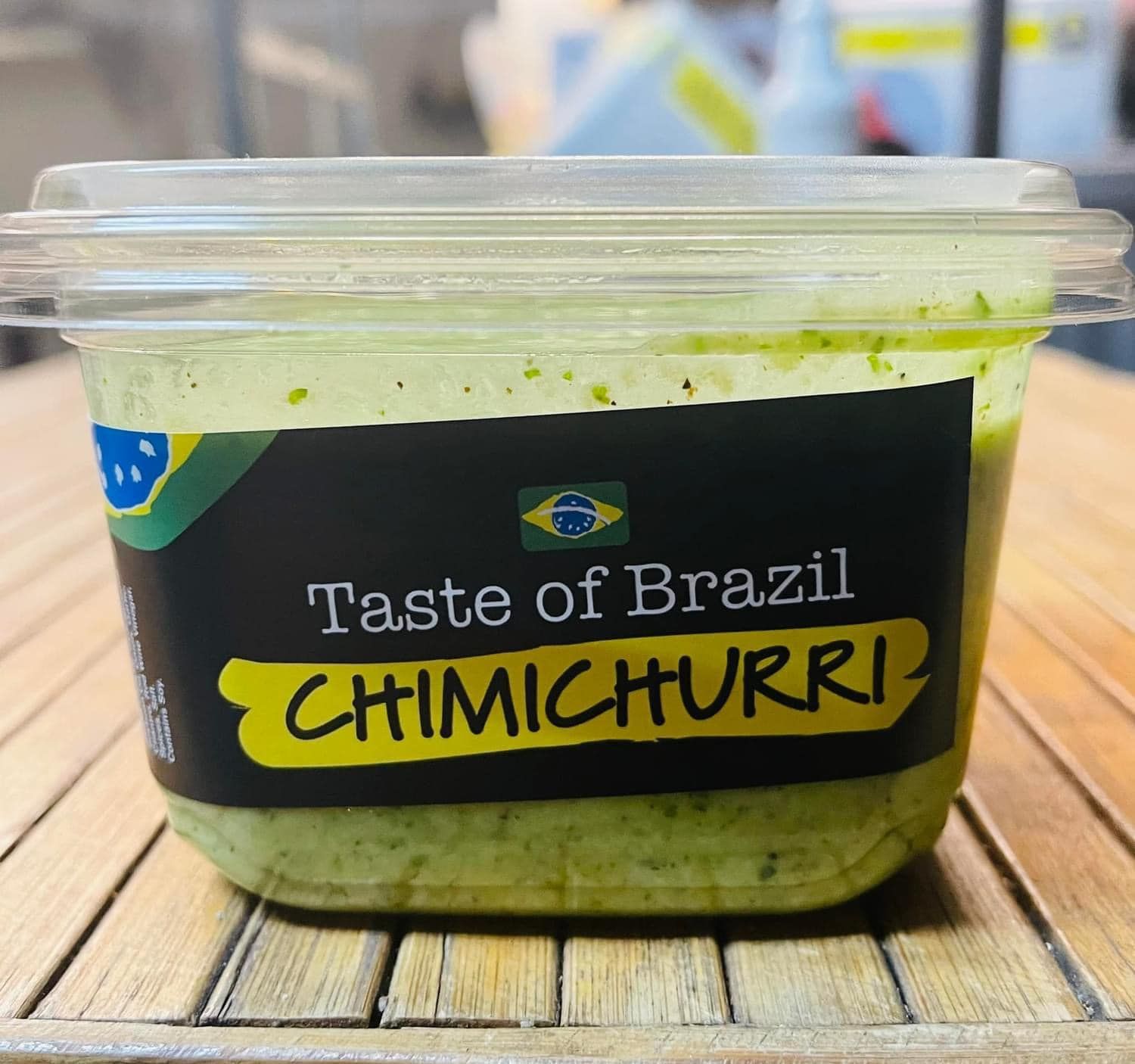 A container of taste of brazil chimichurri sits on a wooden table