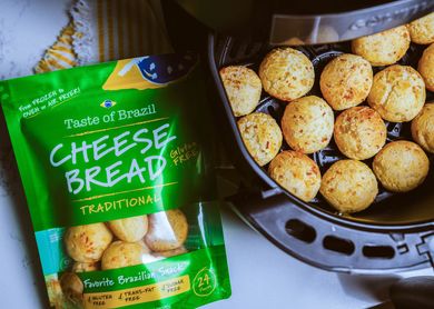 A bag of cheese bread is sitting next to an air fryer filled with cheese bread balls.