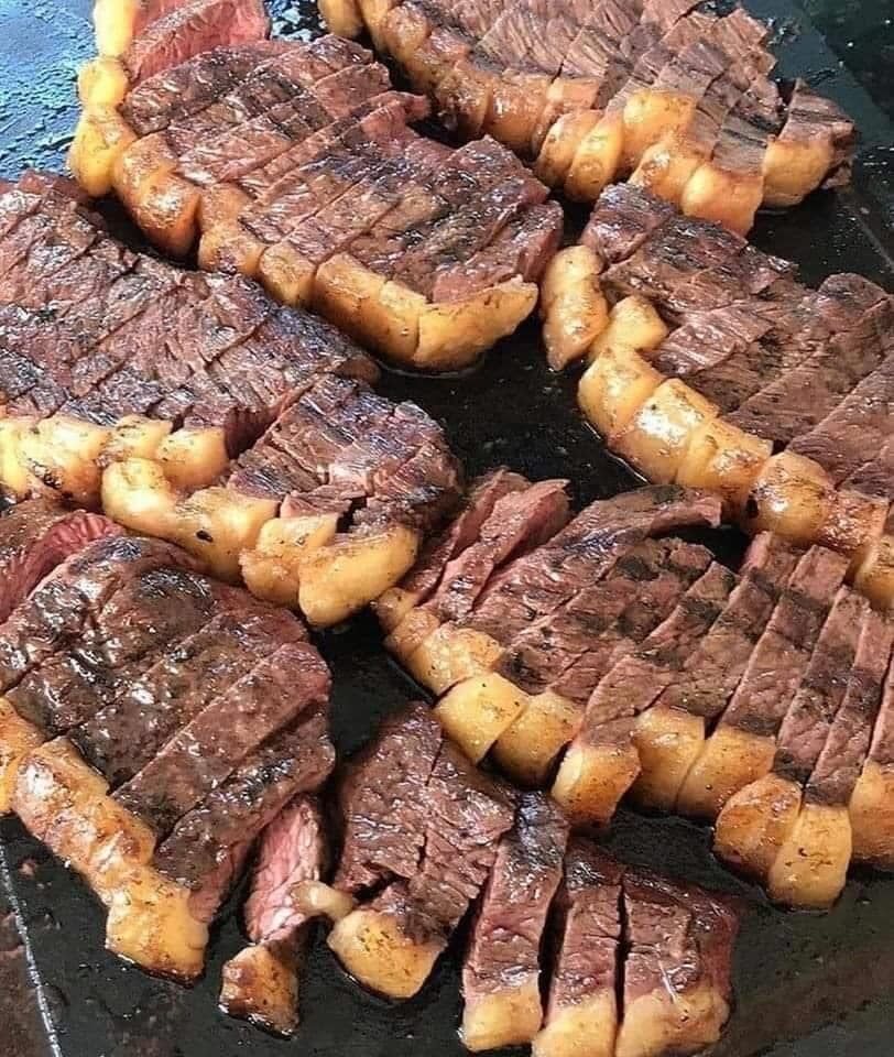 A close up of a plate of steak on a grill.