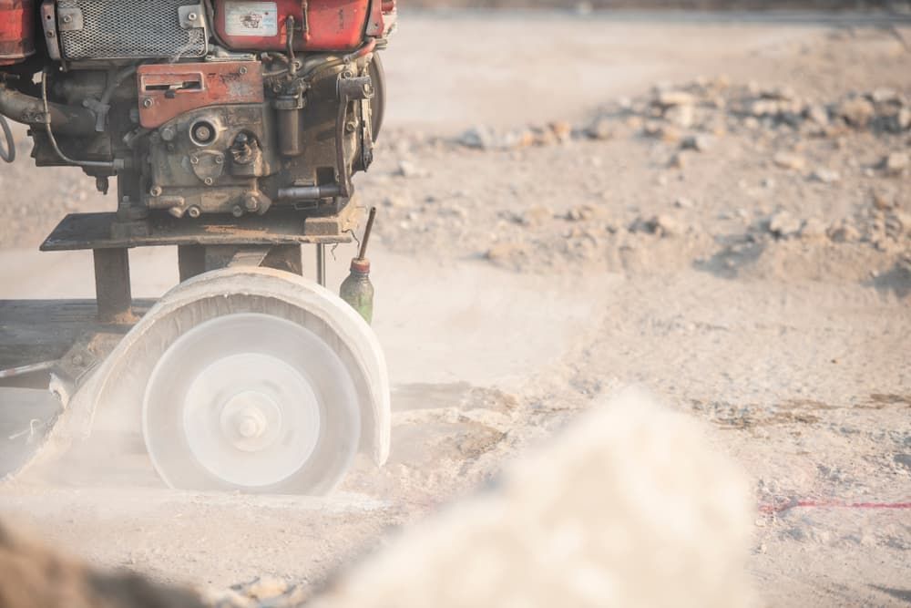 A Tractor Is Cutting Asphalt on A Dirt Road — Albury Demolitions in Lavington, NSW