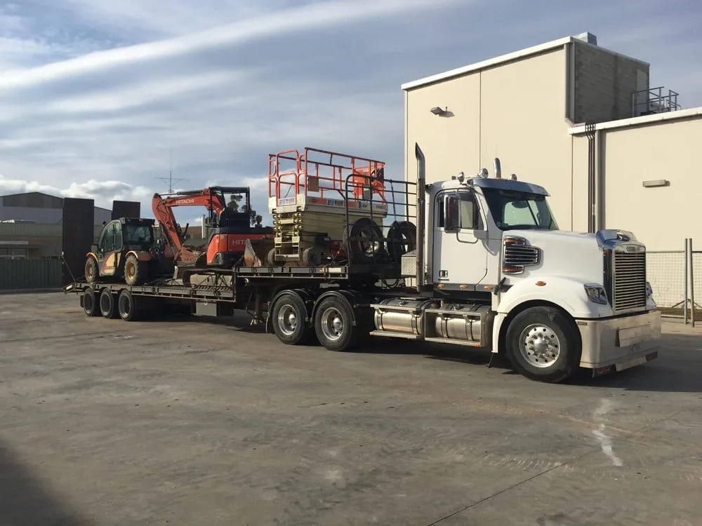 A semi truck is carrying a forklift on a flatbed trailer — Albury Demolitions in Wangaratta, NSW