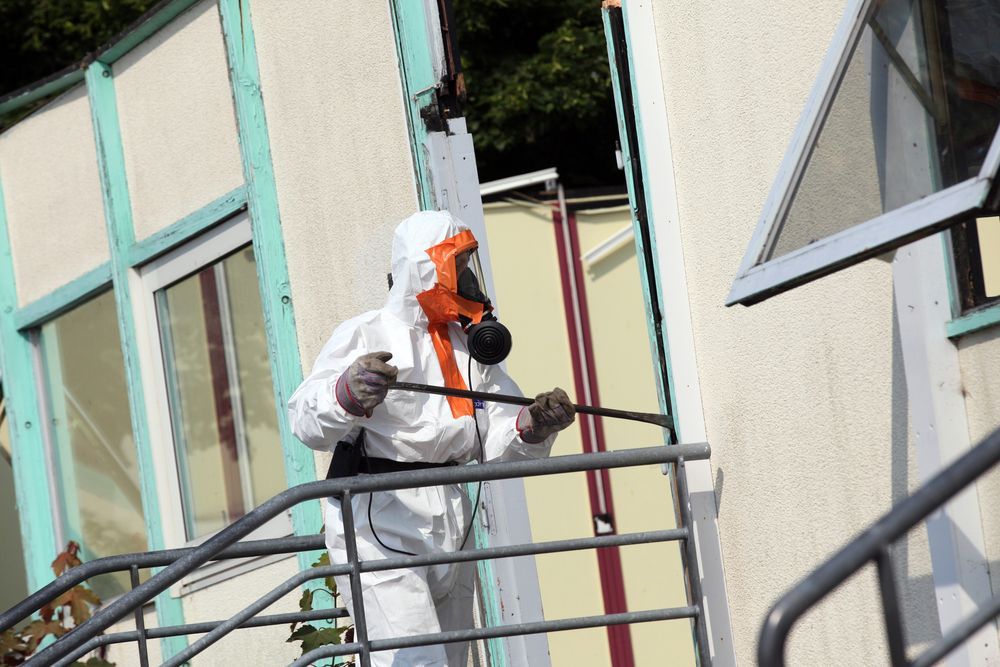 A Man in A Protective Suit Is Working on A Brick Wall — Albury Demolitions in Holbrook, NSW