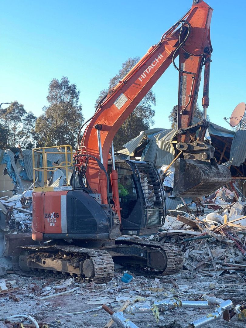 A Large Yellow Excavator Is Demolishing a Building — Albury Demolitions in Beechworth, NSW