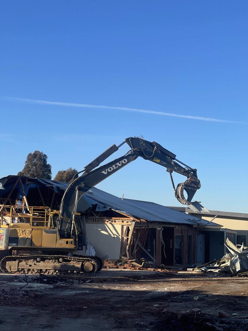 A Large Yellow Excavator Is Demolishing a Building — Albury Demolitions in Lavington, NSW