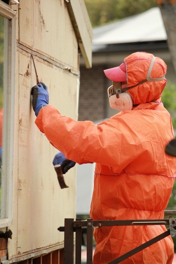 A Man in A Protective Suit Is Working on A Brick Wall — Albury Demolitions in Beechworth, NSW