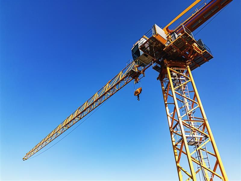 Yellow tower crane against a clear blue sky.