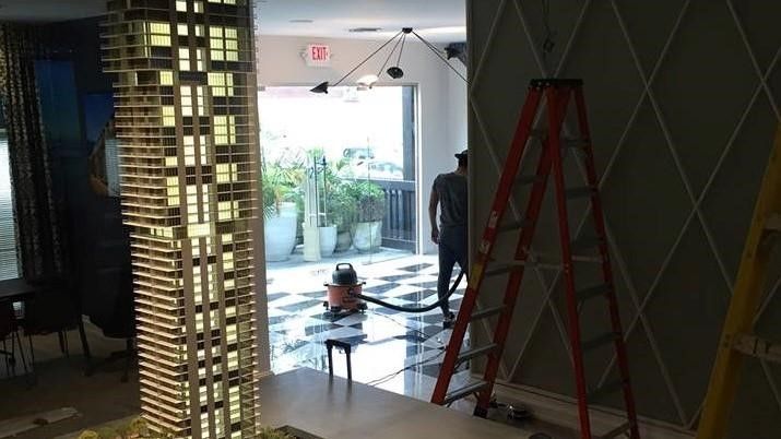 A Man is Standing Next to a Ladder in a Room with a Model of a Building - Miami, FL - Epiclean Profe