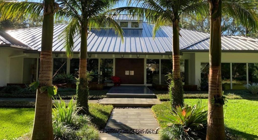 A Large White House with a Metal Roof and Palm Trees in front of it - Miami, FL - Epiclean Professio