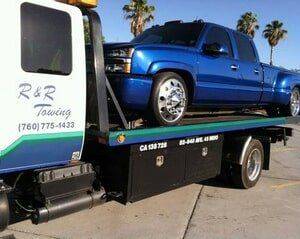 Blue pickup truck on a tow truck platform with 